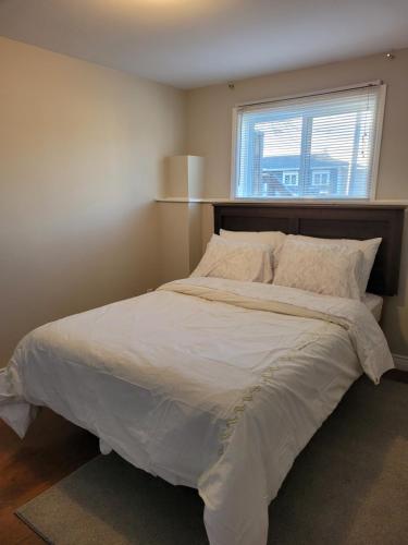 um quarto com uma grande cama branca e uma janela em Full 1-bedroom apartment em St. John's