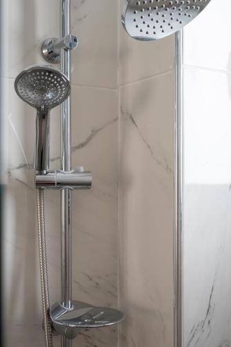 a shower with a shower head next to a glass door at PROPAN CITY SUITES in Volos