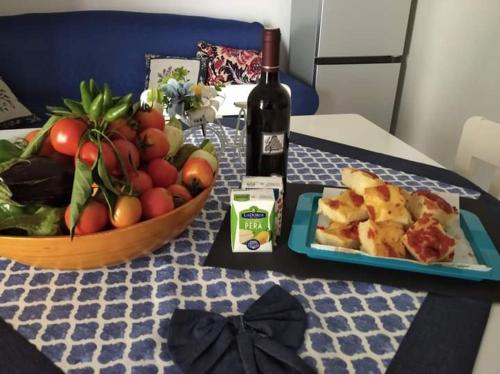 una mesa con una bandeja de fruta y una botella de vino en Da Zia Betty casa vacanza, en Maruggio