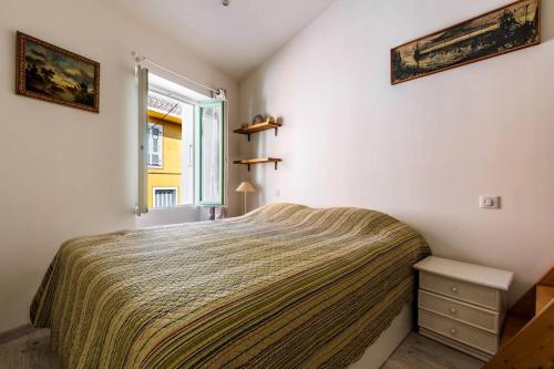een slaapkamer met een bed en een raam bij Cocon dans la vieille ville in Villefranche-sur-Mer