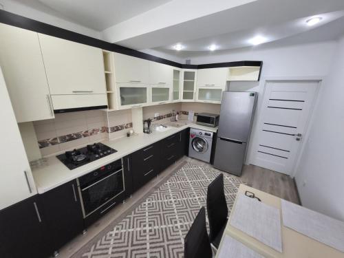 a kitchen with white cabinets and a washer and dryer at Apartment Buiucani in Chişinău