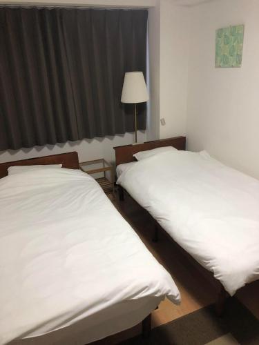 duas camas num quarto com lençóis brancos em HOTEL LUCKY - Vacation STAY 49954v em Osaka