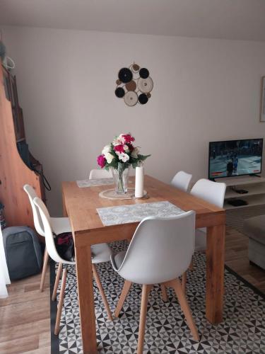 una mesa de comedor con sillas blancas y un jarrón de flores en Charmant appartement T2 parc JB Lebas, en Lille