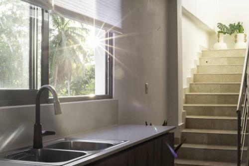 a kitchen with a sink and a window and stairs at New Beachfront Penthouse Punta Popy in Las Terrenas