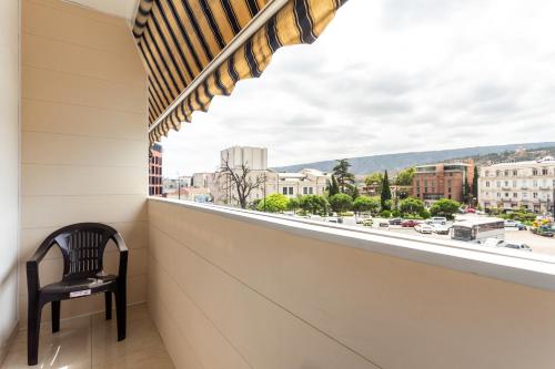 a chair sits on a balcony with a view of a city at Prime location Apartment with Three Bedroom in Tbilisi City