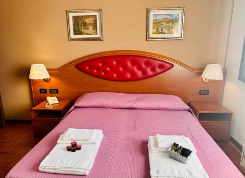 a bedroom with a pink bed with two towels at B&B Banatium in Tezze sul Brenta