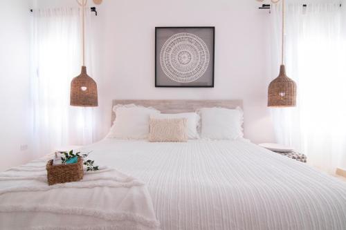 a white bedroom with a large bed with white sheets at New Beachfront Penthouse Punta Popy in Las Terrenas