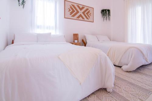 two beds in a white room with white sheets at New Beachfront Penthouse Punta Popy in Las Terrenas