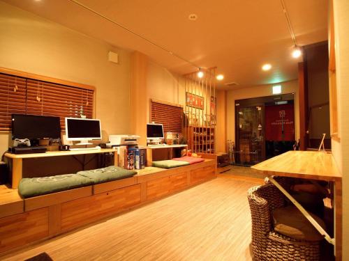 a living room with a couch and two monitors at Guesthouse Nara Komachi in Nara