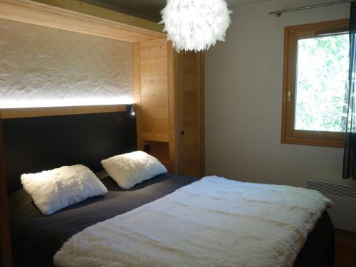- une chambre avec un lit avec deux oreillers et une fenêtre dans l'établissement Appartement 3 pièces avec balcon et garage proche des pistes - FR-1-459-142, à La Clusaz