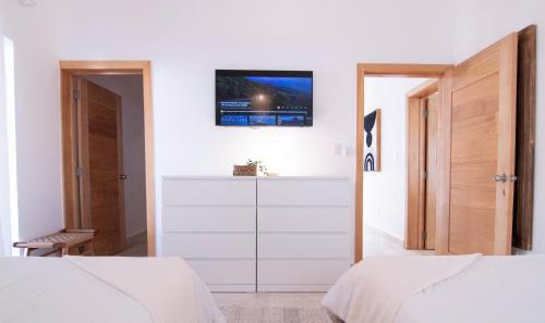 a bedroom with two beds and a tv on the wall at New Beachfront Penthouse Punta Popy in Las Terrenas