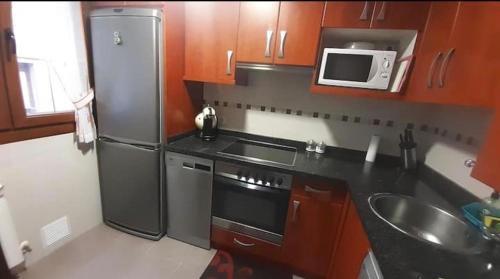 eine Küche mit einem Kühlschrank aus Edelstahl und einer Mikrowelle in der Unterkunft Chuchi house in Ramales de la Victoria