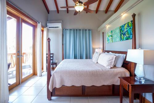 a bedroom with a bed and a table with a lamp at The Villas at Cocoplum in Placencia Village