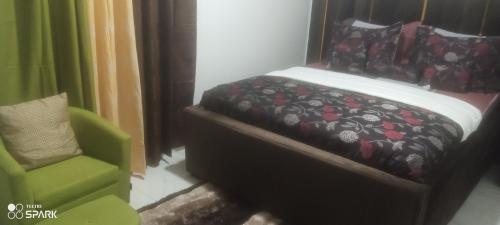 een bed en een groene stoel in een kamer bij George's property in Accra