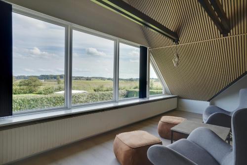 a room with large windows and blue chairs at 9 Rooms Amazing Sommerhouse in Børkop