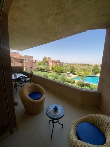 a balcony with chairs and a view of a pool at Marrakech - Prestigia Golf - haut standing in Marrakesh