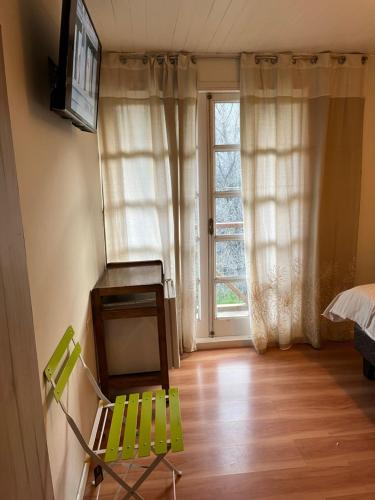une chaise verte dans une chambre avec fenêtre dans l'établissement Alojamiento en San José de Maipo, à Santiago