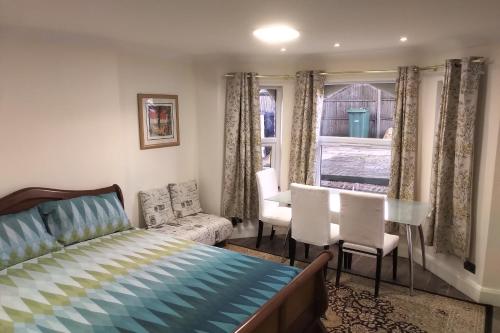 a bedroom with a bed and chairs and a window at Leamington Park Studio with Parking in London