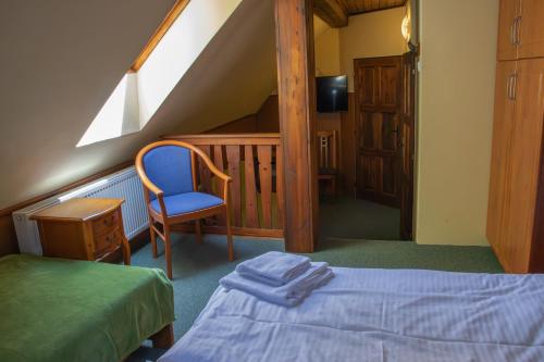 a bedroom with a bed and a chair and a staircase at Penzion Zvonice Hojná Voda in Horní Stropnice