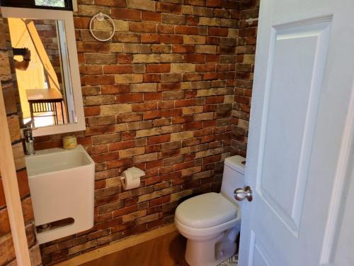 a bathroom with a brick wall and a toilet at Glamping Town in Otinapa