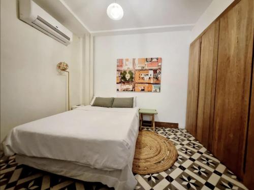 Un dormitorio con una cama blanca y un armario de madera. en AmazINN Places Casa Bandera II, en Panamá