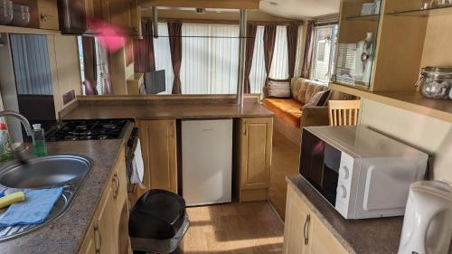 a kitchen in an rv with a sink and a stove at Park Home at Lyons Winkups Holiday Park N.Wales in Kinmel Bay