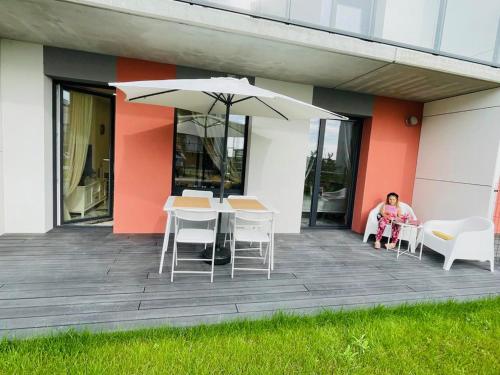 a woman sitting on a deck with an umbrella at Baltijos apartamentai in Klaipėda