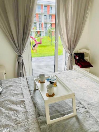 a bedroom with a white bed with a table on it at Baltijos apartamentai in Klaipėda