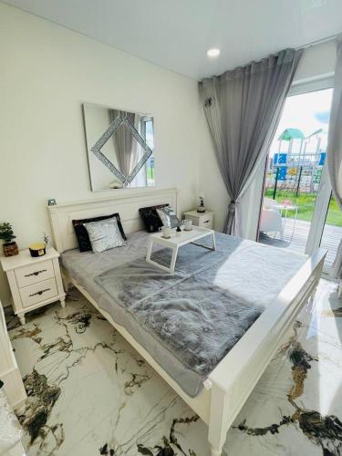 a white bedroom with a large bed and a mirror at Baltijos apartamentai in Klaipėda