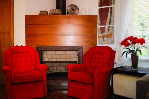 two red chairs in a living room with a fireplace at No Centro de Gramado bem pertinho do Natal Luz 77 in Gramado