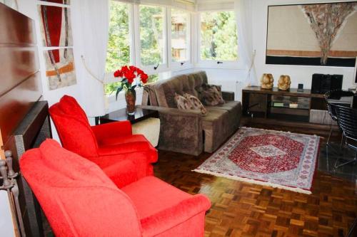 a living room with red chairs and a couch at No Centro de Gramado bem pertinho do Natal Luz 77 in Gramado