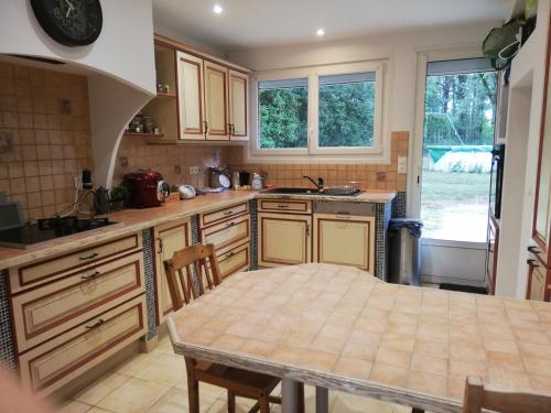 uma cozinha com uma mesa e uma bancada em Grande maison au calme au cœur d un bois em Ferrières