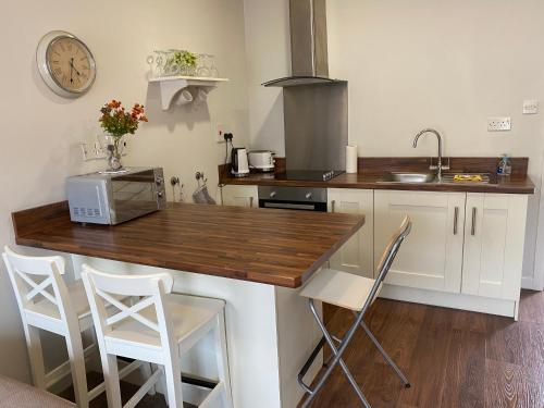 a kitchen with a counter with a microwave and chairs at Irvinestown Fermanagh 2 Bedroom Apartment in Irvinestown