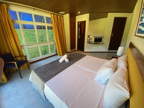 a bedroom with a large bed and a large window at Hotel Fazenda Bonanza in Engenheiro Paulo de Frontin