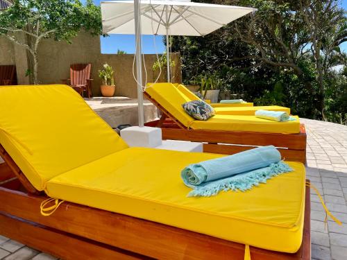 two yellow beds with an umbrella on a patio at COCOVIEW BEACH HOUSE in Southbroom