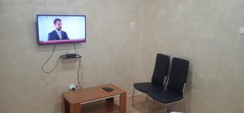 Zimmer mit einem TV an einer Wand mit einem Stuhl und einem Tisch in der Unterkunft Mikassa room in Niš