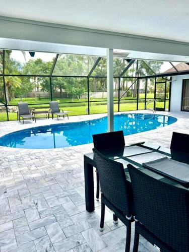 une piscine avec des chaises et une table ainsi qu'une terrasse dans l'établissement Luxurious pool home in Palm Beach County, Florida, à Wellington