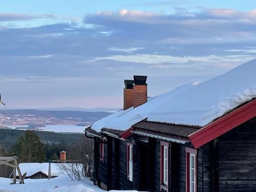 a log cabin with snow on the roof at Fryksås Hotell & Gestgifveri in Fryksås