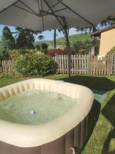 a hot tub in a backyard with an umbrella at Splendido rustico nella Langa in Clavesana