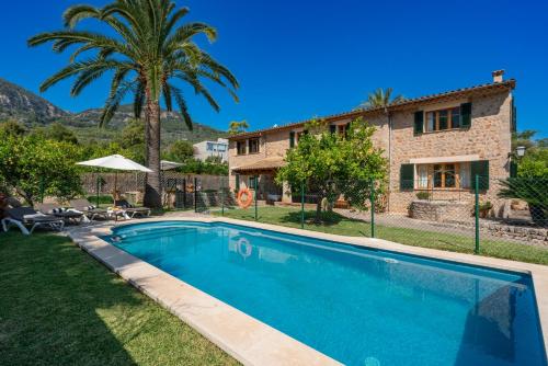 a villa with a swimming pool in front of a house at Sa Finqueta, Luxury Elegant Mansion with breathtaking views of Soller in Sóller
