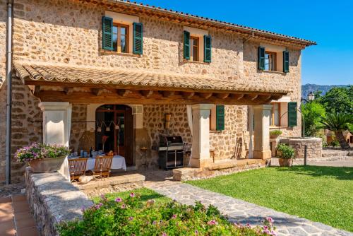 a stone house with green shutters and a garden at Sa Finqueta, Luxury Elegant Mansion with breathtaking views of Soller in Sóller