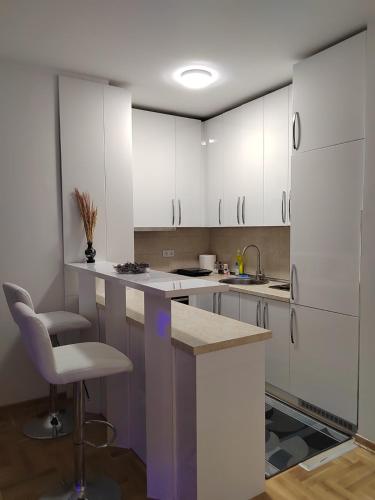 a kitchen with white cabinets and a sink and a chair at Apartman Mančić in Pirot