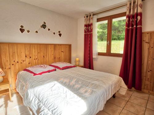 una camera da letto con un grande letto con tende rosse di Appartement cosy 3 pièces au pied des pistes, parking privé - FR-1-505-104 a Notre-Dame-de-Bellecombe
