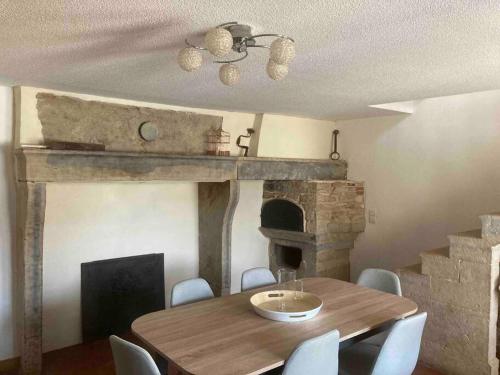 una sala da pranzo con tavolo e camino di Maison de village a Audelange