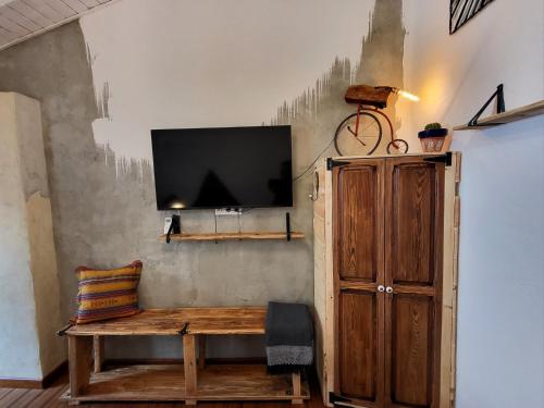 a living room with a wooden bench and a tv on a wall at Casa de Koras in Cullera