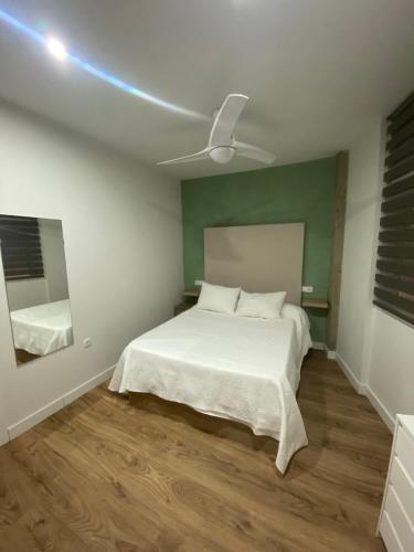 1 dormitorio con cama blanca y ventilador de techo en Apartamento Turístico Campo de la Verdad en Córdoba