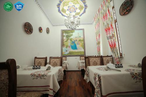 uma sala de jantar com duas mesas e um lustre em Мы открылись! Hotel Guli em Bukhara