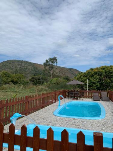 a swimming pool in a yard with a wooden fence at Chalé Topázio no Recanto Diamantina entre Palmeiras e Capão in Palmeiras