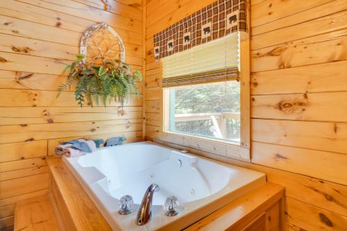 eine weiße Badewanne in einem Holzbadezimmer mit Fenster in der Unterkunft Pigeon Forge Cabin with Hot Tub 5 Mi to Dollywood in Pigeon Forge