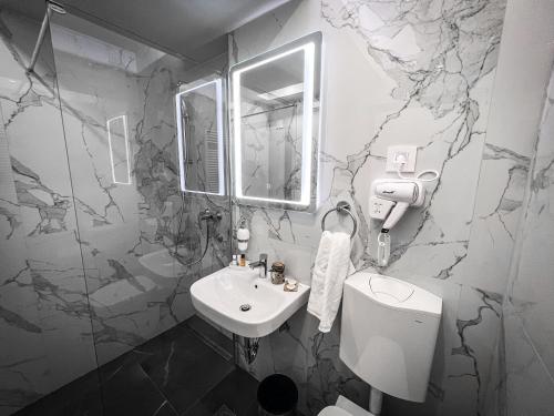 ラクタシにあるHotel Laktašiの白いシンクと大理石の壁が備わるバスルーム